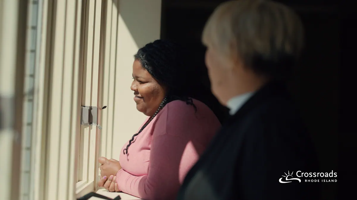 Two women in conversation beside a sunlit window during a shoot