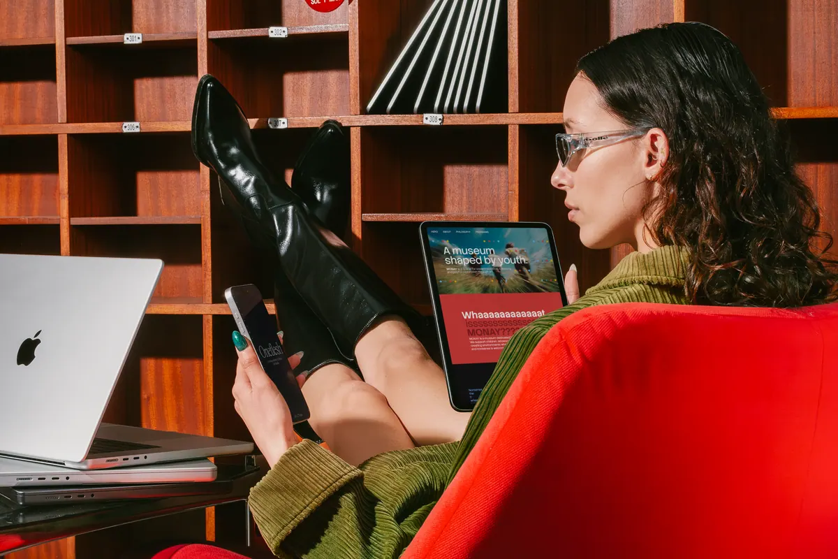 A woman browsing a website on a tablet in a red chair