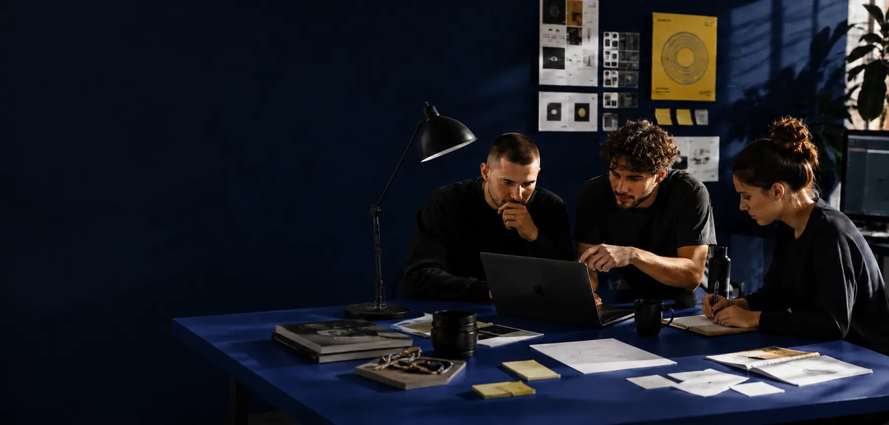A creative team reviewing work around a table in a blue studio