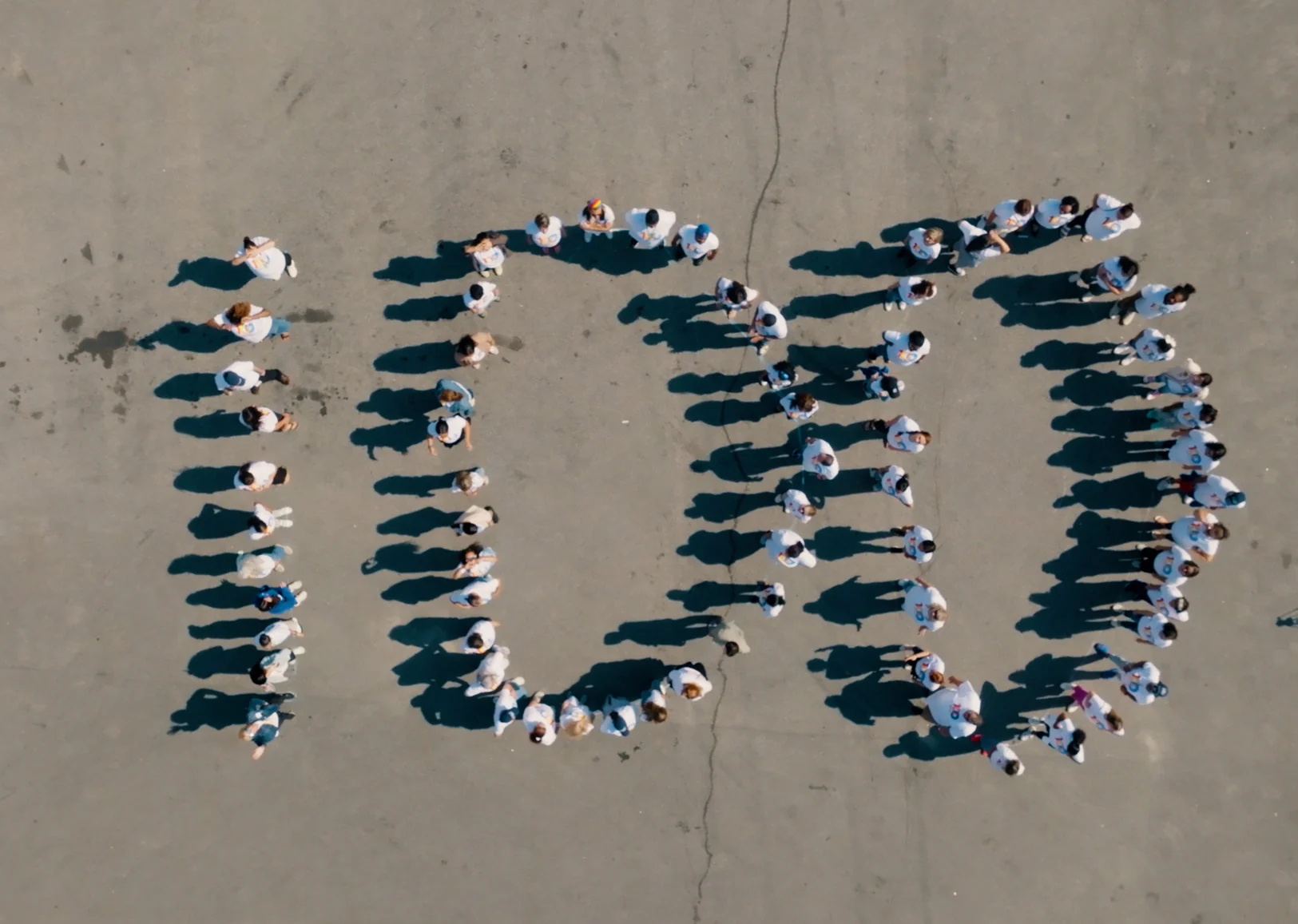 Seen from above, people in United Way of Rhode Island centennial shirts standing together in the shape of the number 100